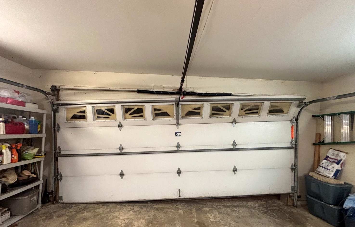 Crooked off-track garage door photographed before repair